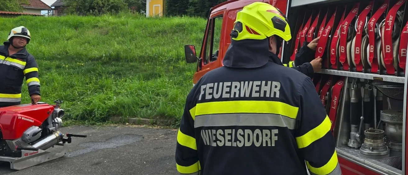 Ein Feuerwehrmann aus Wieselsdort überprüft die Ausrüstung eines roten Feuerwehrwagens.