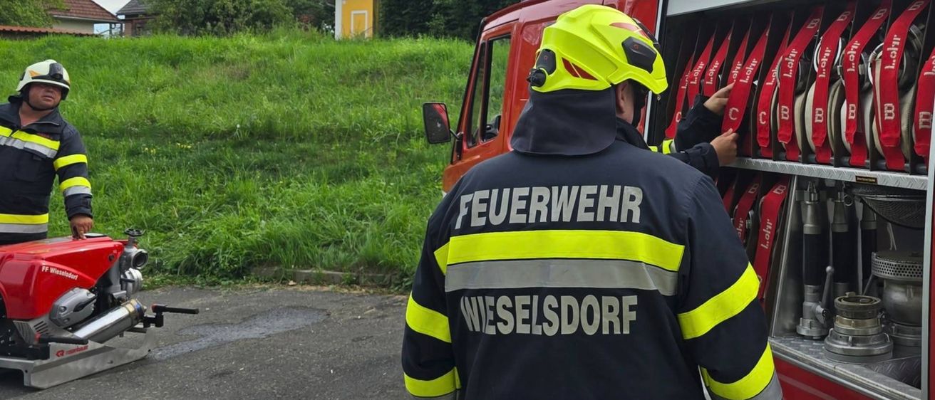 Ein Feuerwehrmann aus Wieselsdort überprüft die Ausrüstung eines roten Feuerwehrwagens.