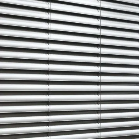 Ein Nahaufnahme von weißen horizontalen Jalousien, ordentlich angeordnet und gefaltet, die ein elegantes und organisiertes Erscheinungsbild erzeugen.