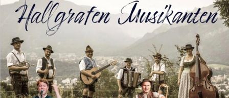 Eine Gruppe von Musikern, die verschiedene Instrumente spielen, steht auf einem Feld mit Bergen im Hintergrund. Der Text lautet '30. Dezember 2025 19 Uhr Einlass 20 Uhr Beginn Gasthaus Dichtlwiert.' Der Eintritt beträgt 15 Euro.