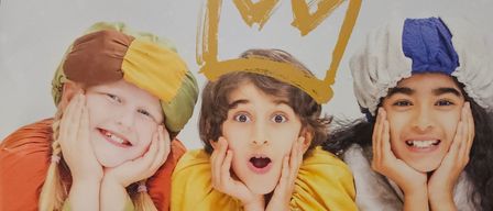 Drei Kinder in mittelalterlichen Kostümen posieren für ein Foto. Das mittlere Kind hat eine Krone auf dem Kopf gemalt. Unten ist eine Website-Adresse sichtbar.