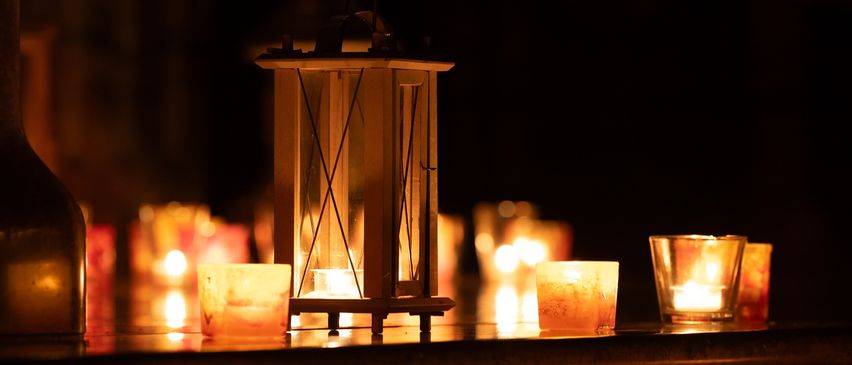 A lantern is lit in the center, with several other candles around it, creating a warm glow in the dark.