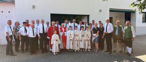 Eine Gruppe von Menschen in weißen Gewändern und Krawatten steht draußen vor einem weißen Gebäude.