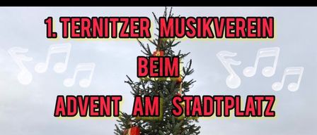 Ein dekorierter Weihnachtsbaum mit roten Geschenken steht auf einem Stadtplatz. Über dem Baum befinden sich Musiknoten und der Text 'Beim Advent am Stadtplatz'. Der Baum lädt vom 5. bis 7. und 8. Dezember von 15 bis 20 Uhr ein.