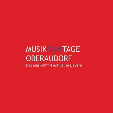 Ein roter Plakat mit weißem Text 'MusikFilmTage Oberaudorf' und 'Das Musikfilm-Festival in Bayern'. Der Text ist zentriert.