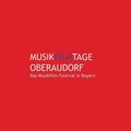 Ein roter Plakat mit weißem Text 'MusikFilmTage Oberaudorf' und 'Das Musikfilm-Festival in Bayern'. Der Text ist zentriert.