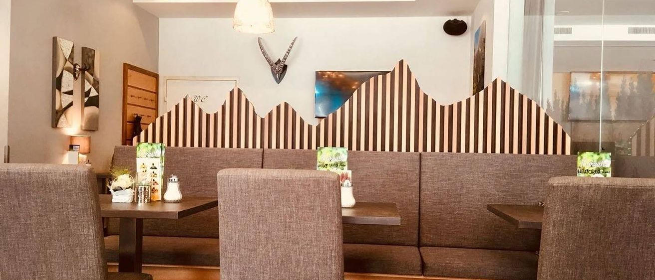 Ein gemütliches Restaurant mit braun-weiß gestreiften Wänden, einem montierten Tierkopf und einem Tisch mit Gewürzen.