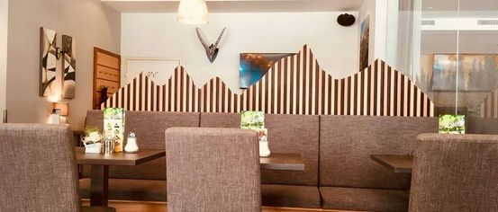 Ein gemütliches Restaurant mit braun-weiß gestreiften Wänden, einem montierten Tierkopf und einem Tisch mit Gewürzen.