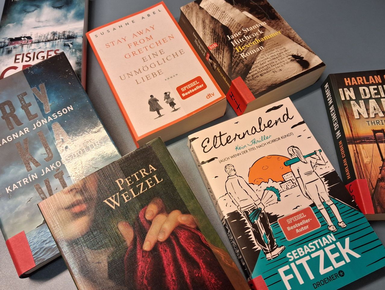 A collection of books, including 'Stay Away from Gretchen', 'Eternal Blend', 'Petra Wezel', and 'Sebastian Fitzek', are arranged on a table. Each book has a distinct cover design.