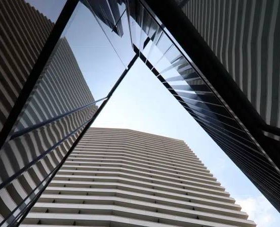 Eine geometrische Anordnung von Wolkenkratzern in einer Stadt mit reflektierenden Oberflächen und geometrischen Mustern an ihren Fassaden.