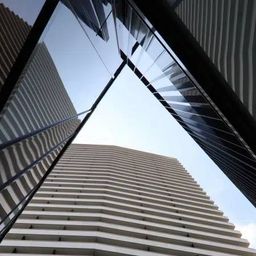 Eine geometrische Anordnung von Wolkenkratzern in einer Stadt mit reflektierenden Oberflächen und geometrischen Mustern an ihren Fassaden.