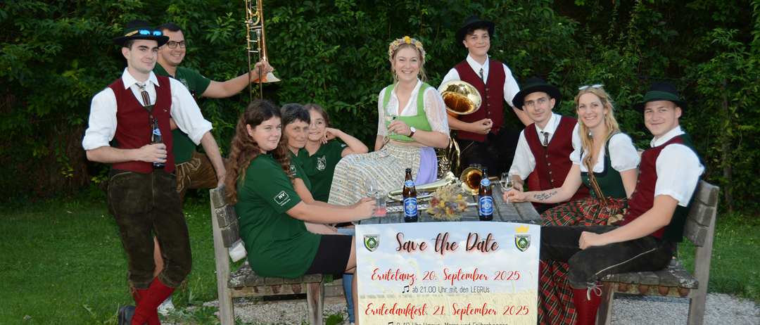 Eine Gruppe von Menschen in traditioneller Kleidung posiert für ein Foto mit Instrumenten. Ein Schild davor sagt 'Save the Date'. Die Veranstaltung findet am 20. und 21. September 2025 statt.