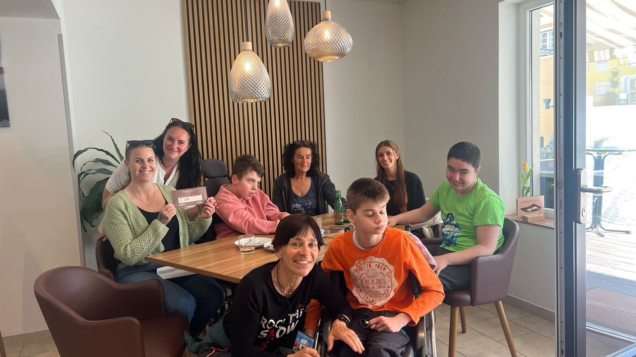 Eine Gruppe von Menschen sitzt um einen Tisch herum, lächelt und posiert für ein Foto.