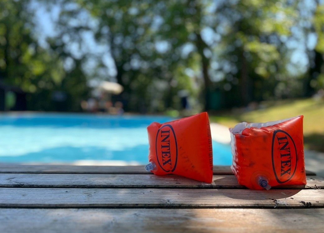 Schwimmflügel von Intex liegen auf Holzplanken neben einem Pool im Freien.