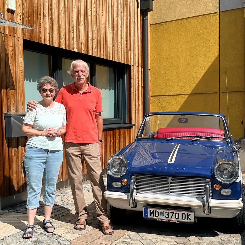 Älteres Ehepaar vor einem blauen Oldtimer-Cabriolet in Österreich