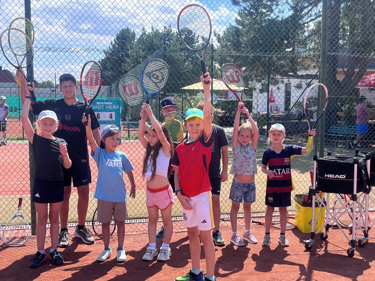 Kinder mit Tennisschlägern auf einem Tennisplatz in Österreich.