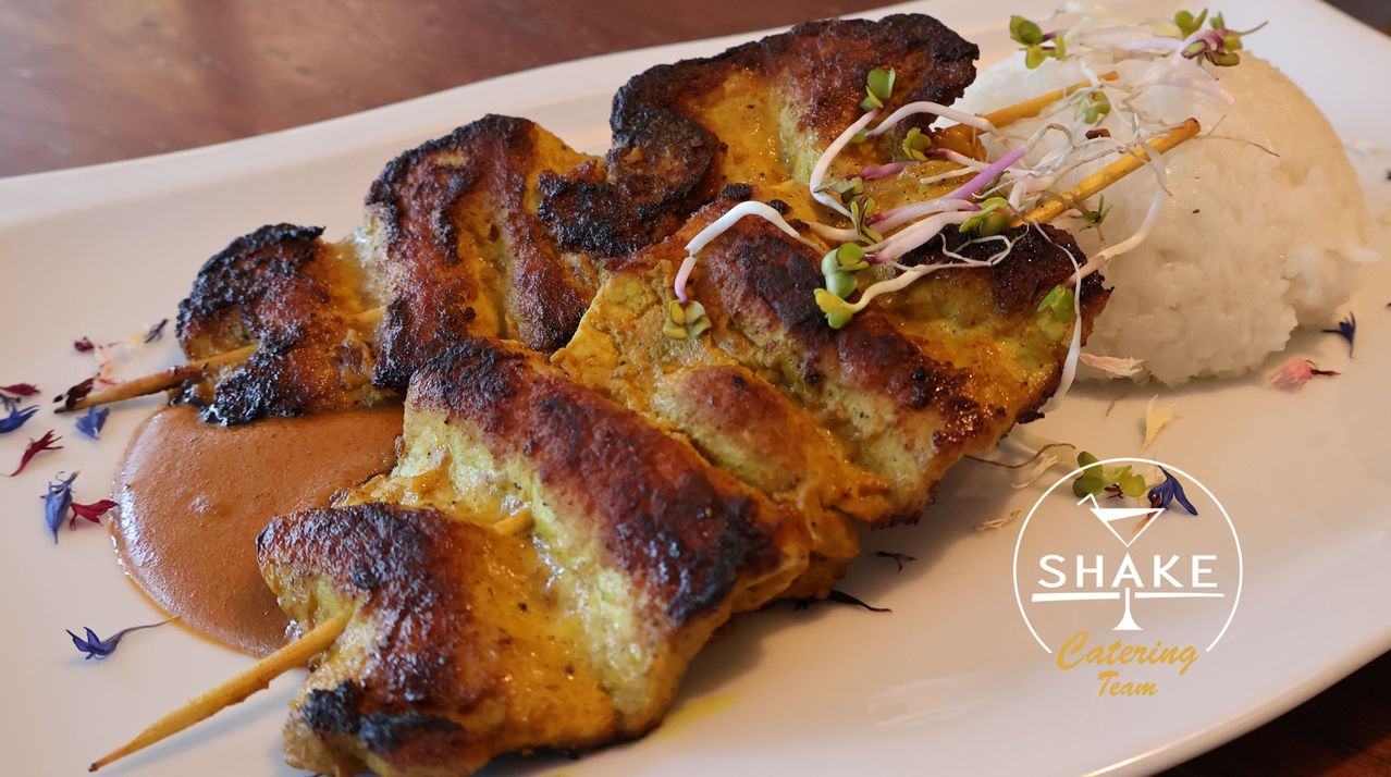 Grilled chicken skewers with a golden-brown crust, garnished with sprouts, served on a white plate.