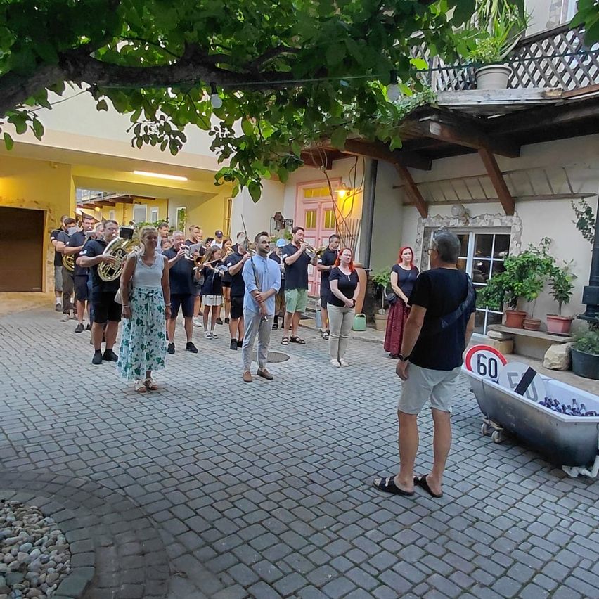 Eine Band spielt auf einer Kopfsteinpflasterstraße vor einem Gebäude mit Balkon und Topfpflanzen.