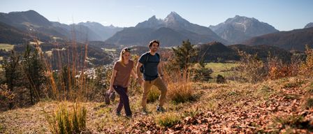 Ein Paar wandert auf einem Bergpfad mit einem wunderschönen Blick auf die Berge im Hintergrund.