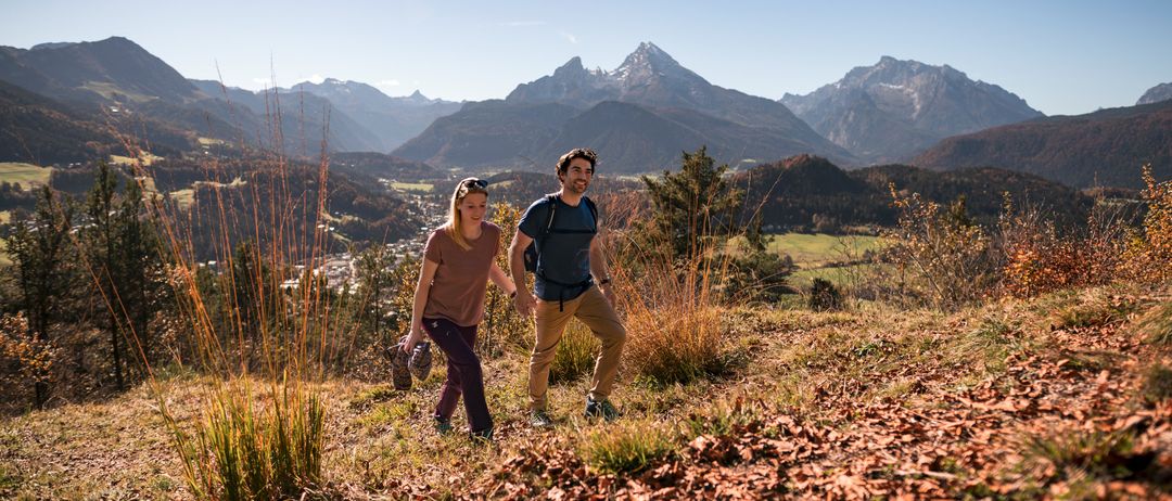 Ein Paar wandert auf einem Bergpfad mit einem wunderschönen Blick auf die Berge im Hintergrund.