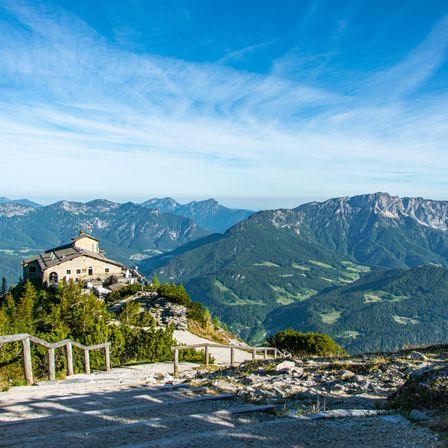 Ein Chalet auf einem Berggipfel mit klarem blauem Himmel und majestätischen Bergen im Hintergrund.