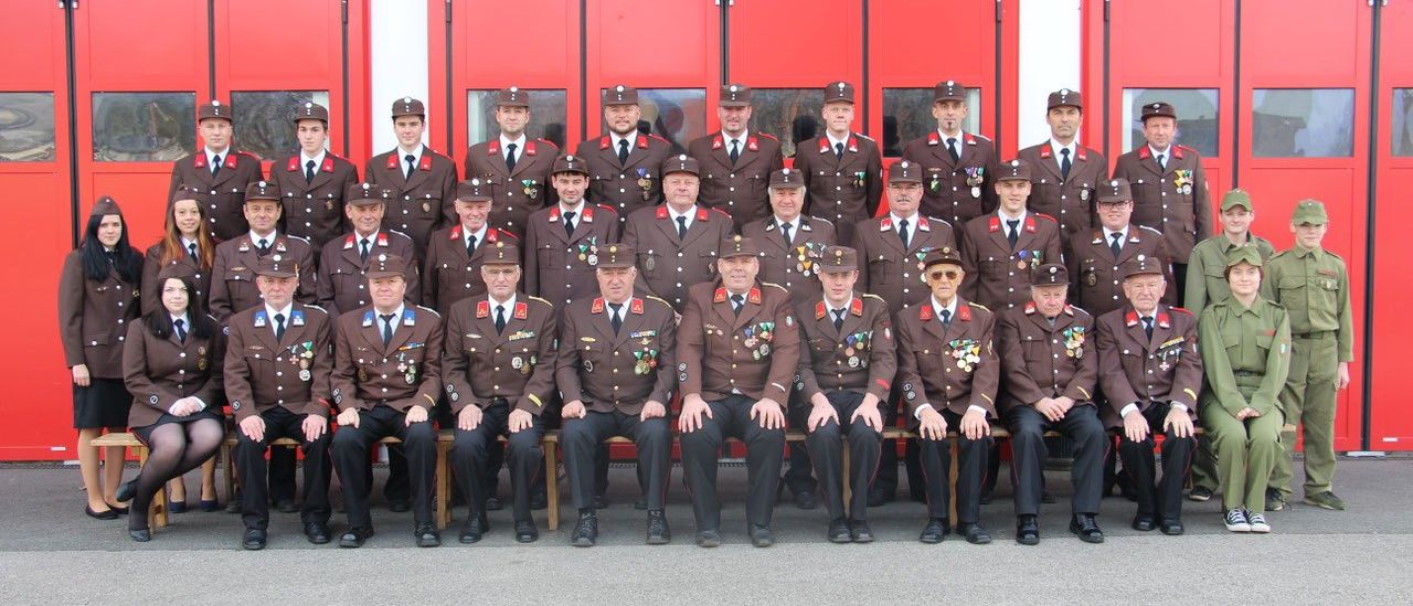 Eine Gruppe uniformierter Männer in Braun und Schwarz posiert für ein Foto vor einem Gebäude mit roten Türen.