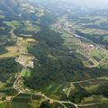 Luftaufnahme einer ländlichen Landschaft mit einer Mischung aus grünen Feldern, dichten Wäldern und kleinen Dörfern. Straßen und eine Autobahn durchqueren das Gebiet und verbinden die Städte.