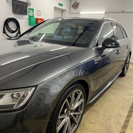 Ein metallgrauer Sedan steht in einer Garage. Das Auto hat ein schlankes Design und eine saubere Außenseite.