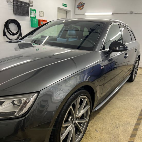 Ein metallgrauer Sedan steht in einer Garage. Das Auto hat ein schlankes Design und eine saubere Außenseite.