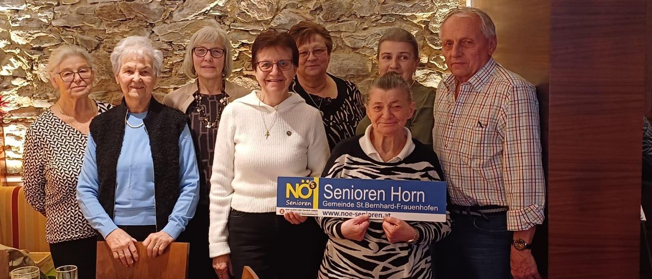 Eine Gruppe älterer Menschen posiert für ein Foto mit einem Schild, das 'Senioren Horn Gemeinde St. Bernhard-Frauenhofen' steht.