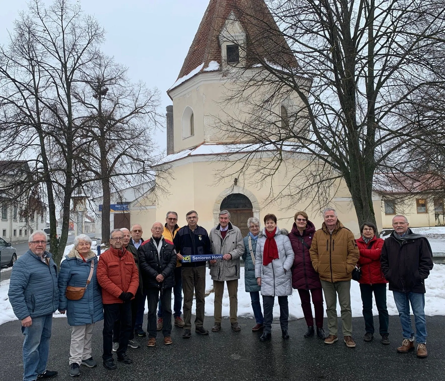 Eine Gruppe von Menschen steht vor einer Kirche und posiert im Winter für ein Foto.