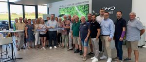 Eine Gruppe von Menschen steht in einem Raum und hält ein blaues Banner mit der Aufschrift NO Senioren Horn. Sie alle lächeln und posieren für ein Foto.