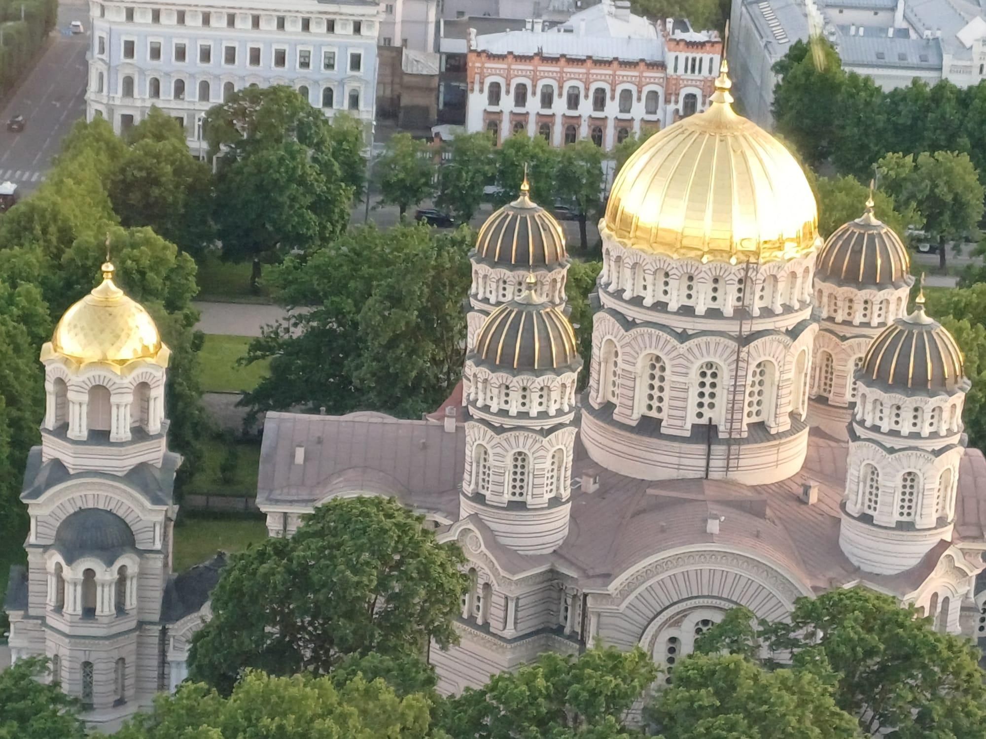 Eine Vogelperspektive einer goldenen Kuppelkathedrale mit filigranen Mustern, umgeben von üppigem Grün und Gebäuden.