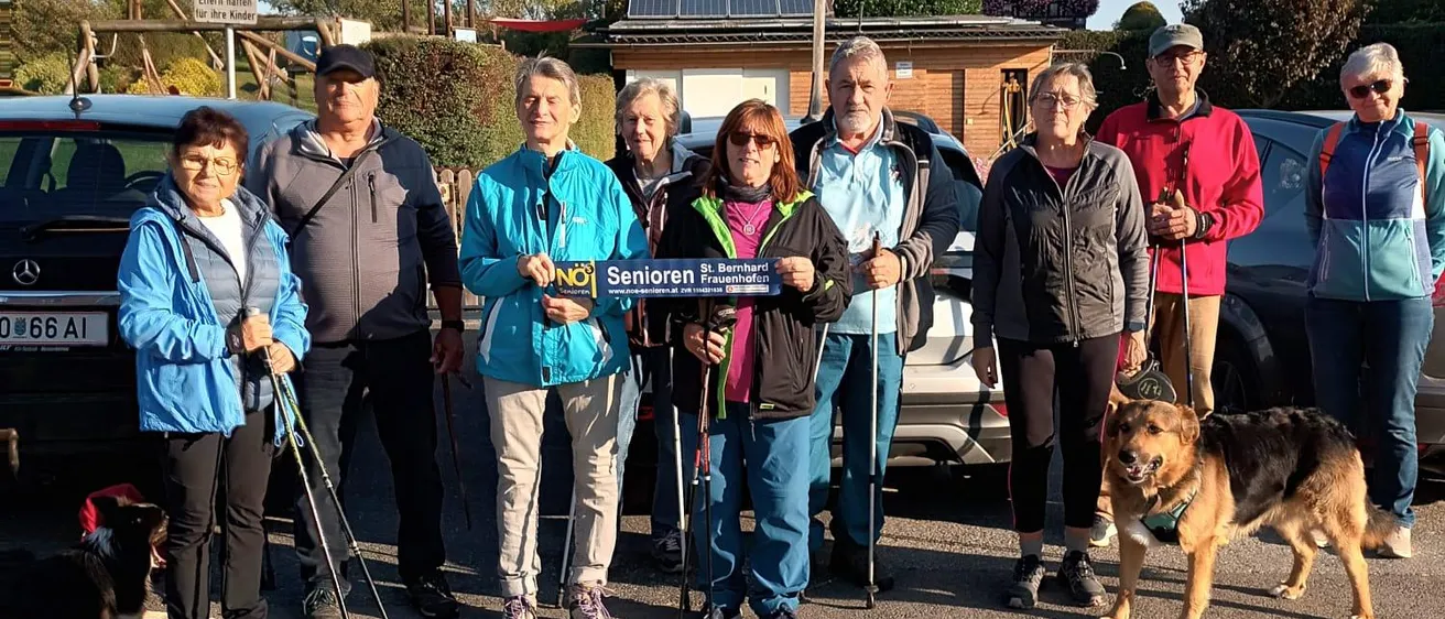 Eine Gruppe von Menschen steht am Straßenrand, hält Stöcke und trägt Sonnenbrillen.