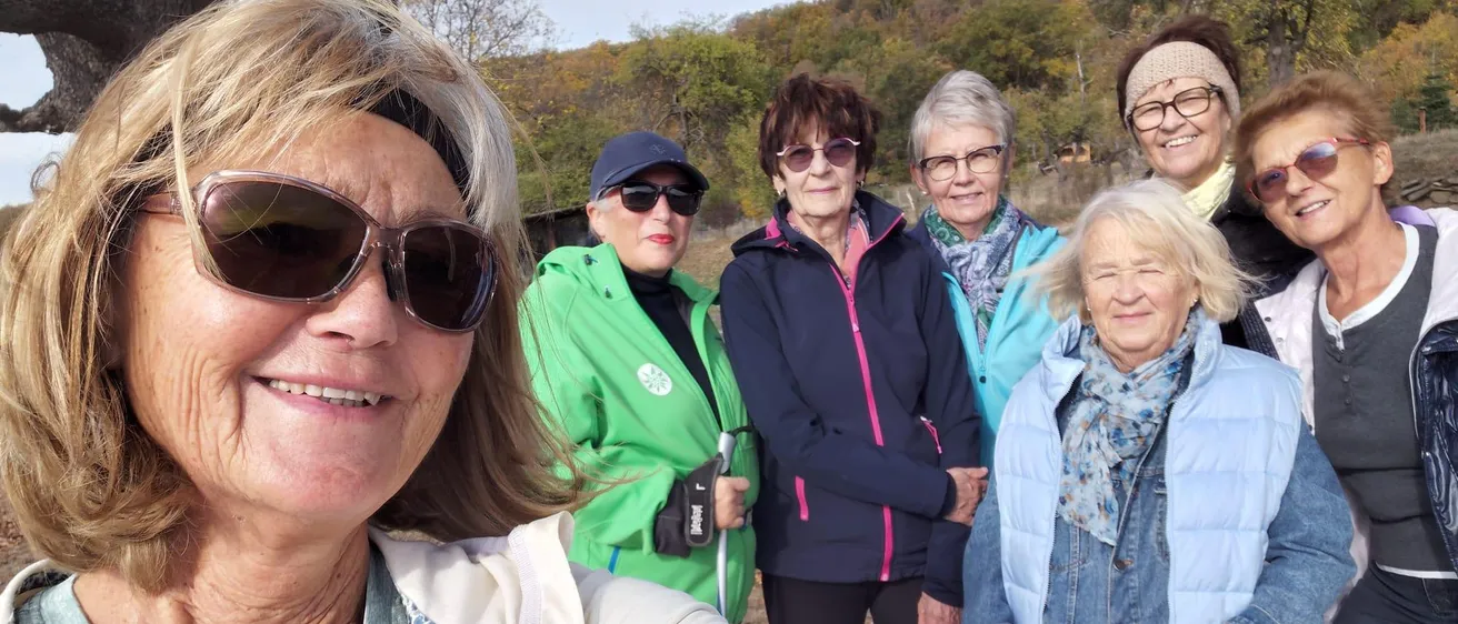 Eine Gruppe älterer Frauen lächelt und posiert für ein Foto im Wald.