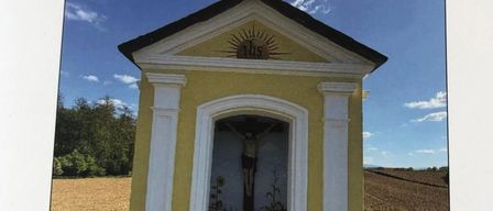 Eine gelbe Kapelle mit einem Kreuz auf der Spitze und dem Bildnis Jesu Christi im Inneren. Die Kapelle ist von Gras und Bäumen umgeben. Das Datum und die Uhrzeit der Veranstaltung sind der 25. Mai 2026 um 18:00 Uhr.