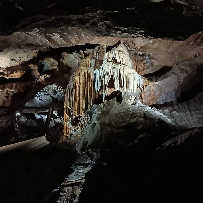 Eine schwach beleuchtete Höhle mit einer großen Stalaktitenformation in der Mitte.