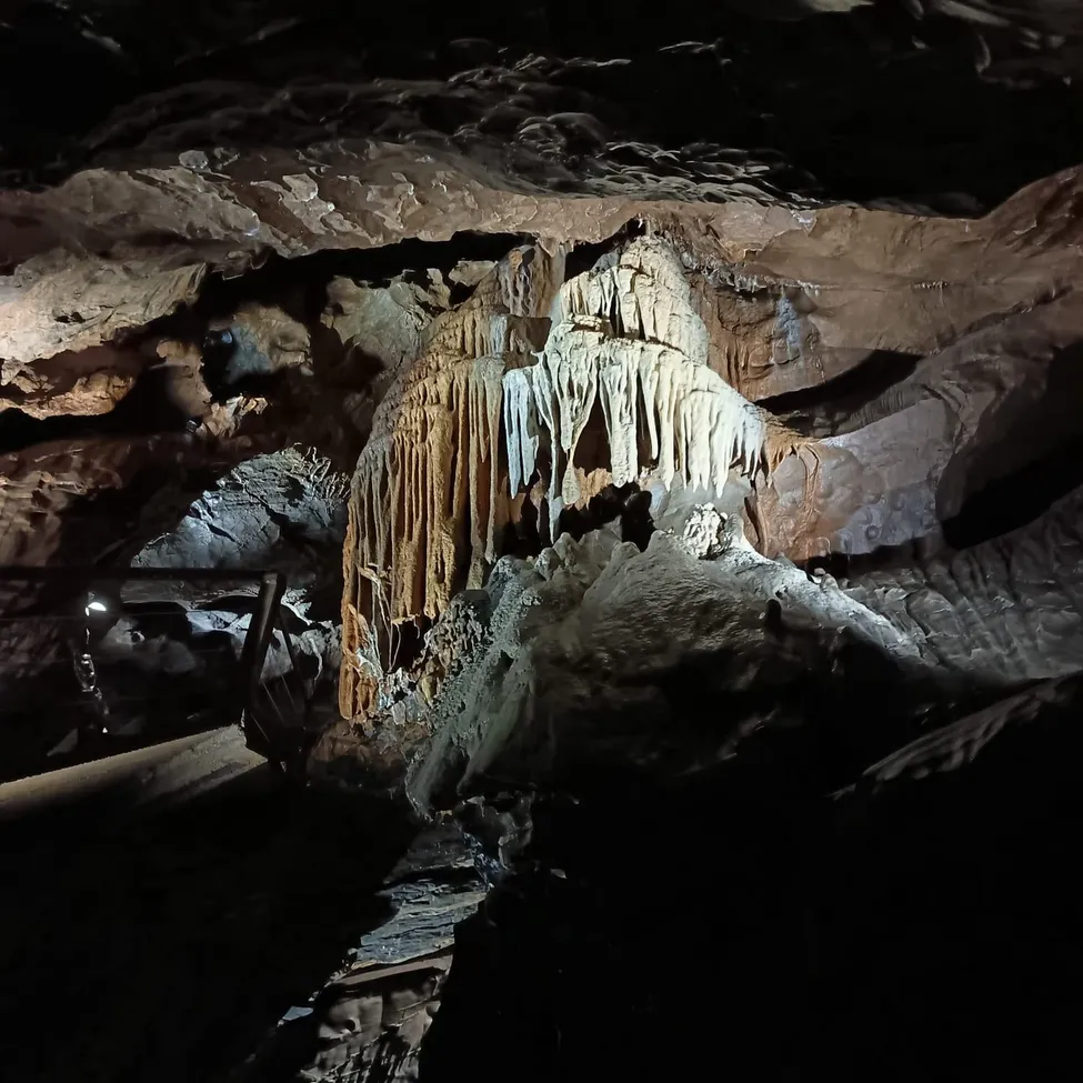 Eine schwach beleuchtete Höhle mit einer großen Stalaktitenformation in der Mitte.