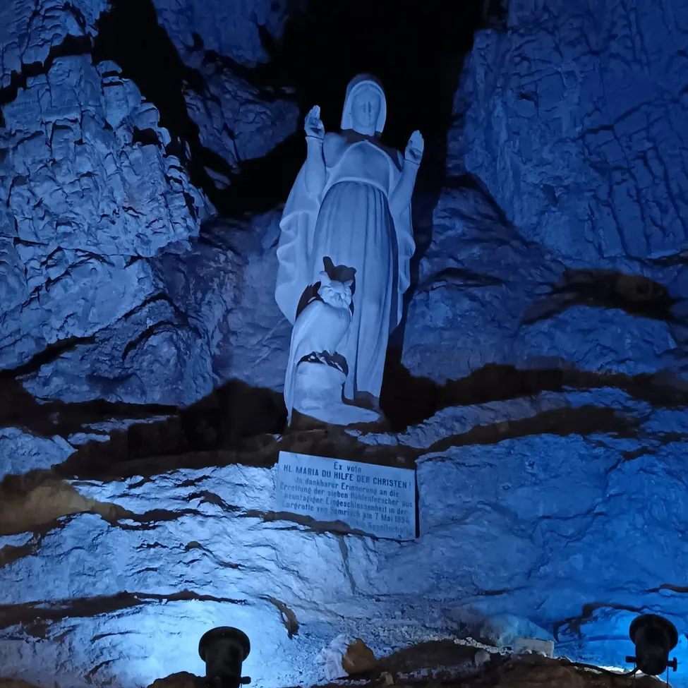 Eine Statue einer Frau wird von blauem Licht in einer Höhle beleuchtet.