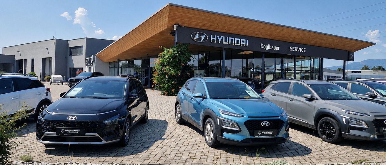 Drei Hyundai-Autos sind vor einem Hyundai-Händler unter einem klaren blauen Himmel geparkt.