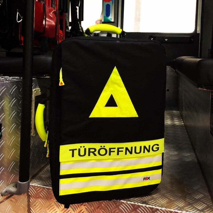 Ein schwarzer und gelber Rucksack mit einem Dreieckssymbol und dem Wort Turoffnung darauf befindet sich in einem Krankenwagen.