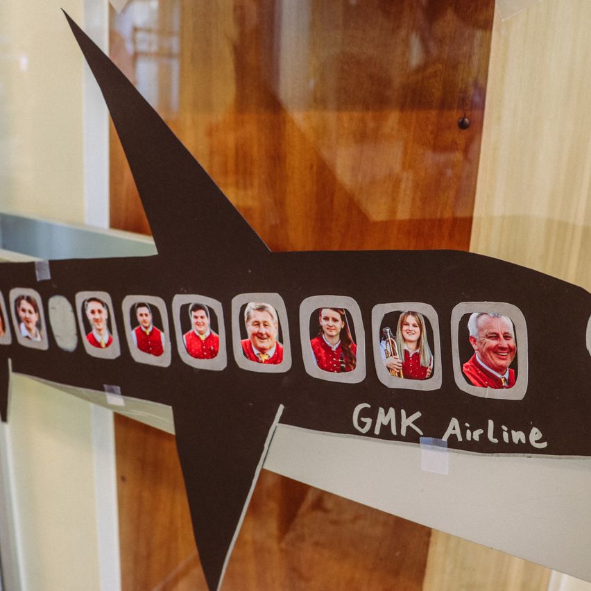 Ein Bild einer Gruppe von Menschen auf einem schwarzen Flugzeugmodell. Es ist eine GMK-Airline mit Fotos von Menschen an den Fenstern.