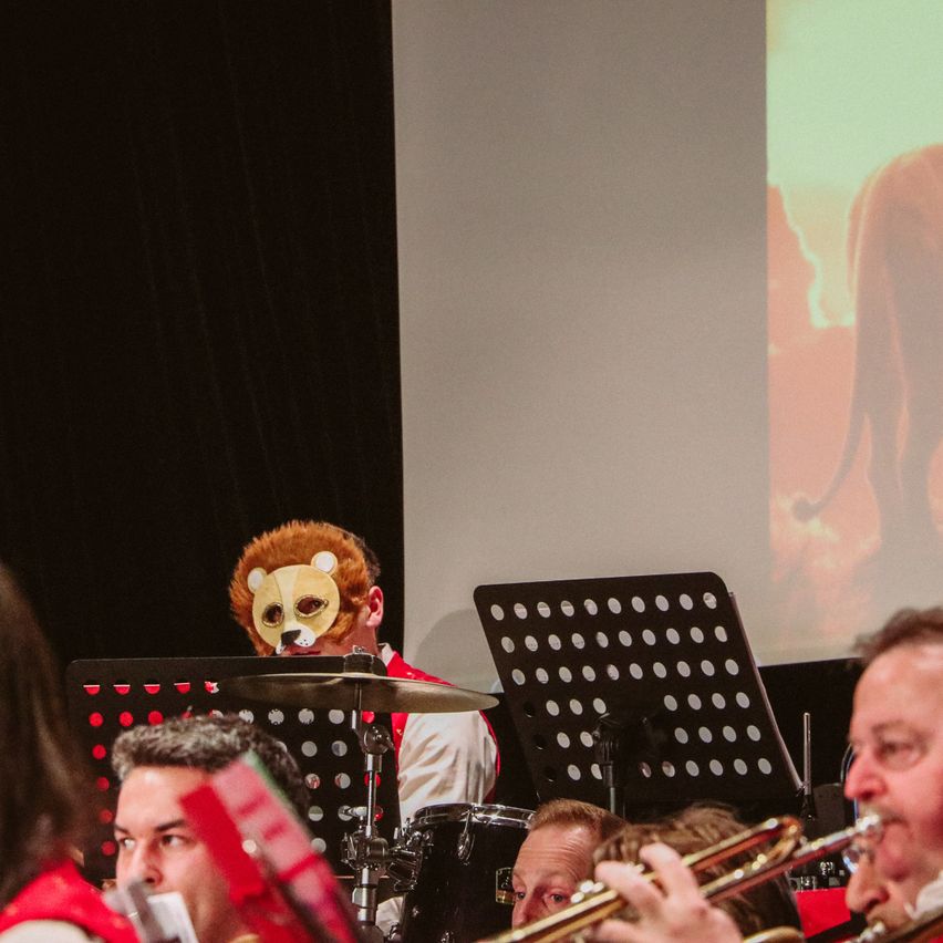 Eine Gruppe von Musikern spielt vor einer Leinwand. Ein Löwe wird auf der Leinwand projiziert.