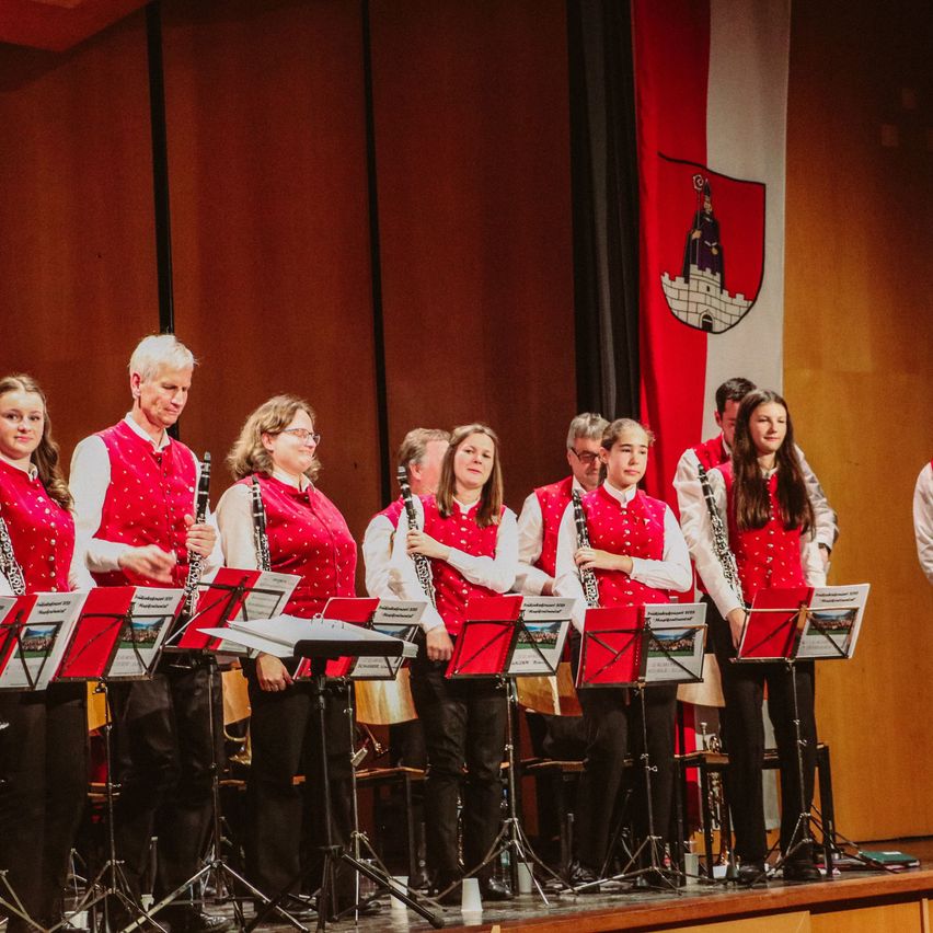 Eine Gruppe von Musikern tritt auf der Bühne auf, trägt rote Westen und hält Klarinetten.