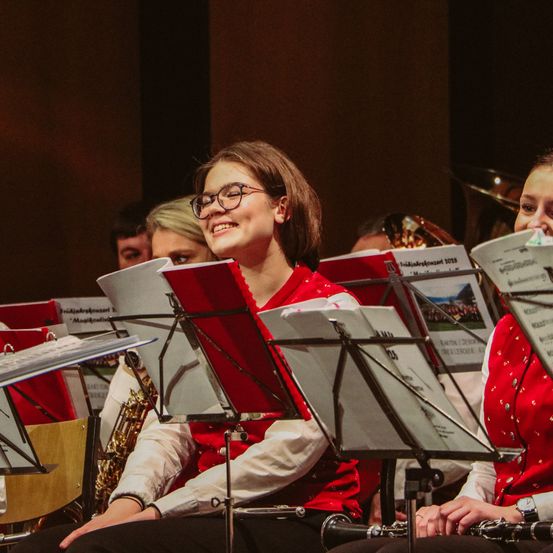 Gruppe junger Musiker mit roten Uniformen und Brillen bei einem Konzert.