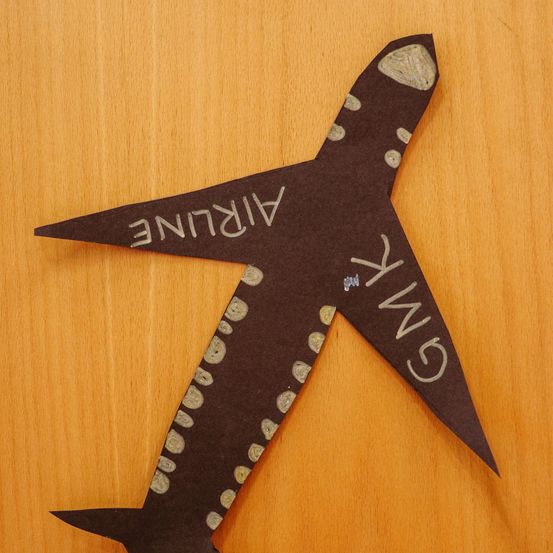 Ein brauner Flugzeug-Papierbastel mit dem Wort Airliner darauf. Die Flügel haben gelbe Punkte.
