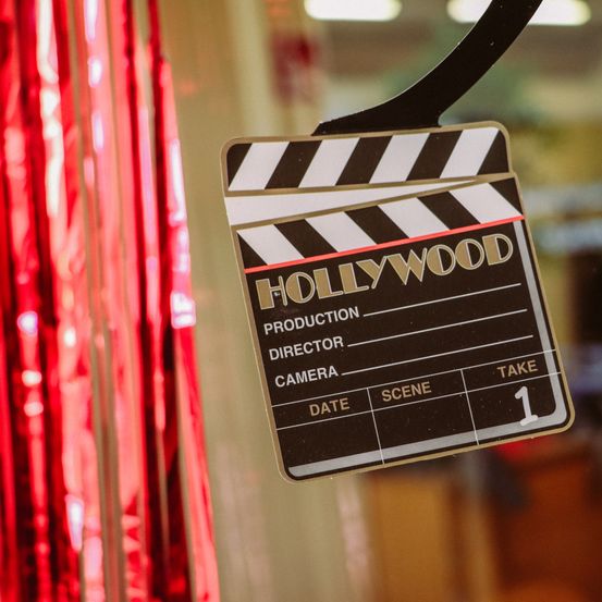 Ein schwarz-weißer Klapsbrett mit dem Wort Hollywood darauf hängt an einer Glastür.