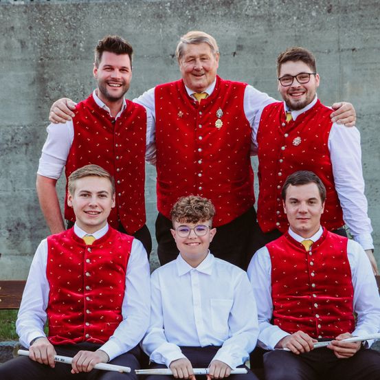 Eine Gruppe von Männern in roten Westen mit weißen Punkten und weißen Hemden posiert für ein Foto.