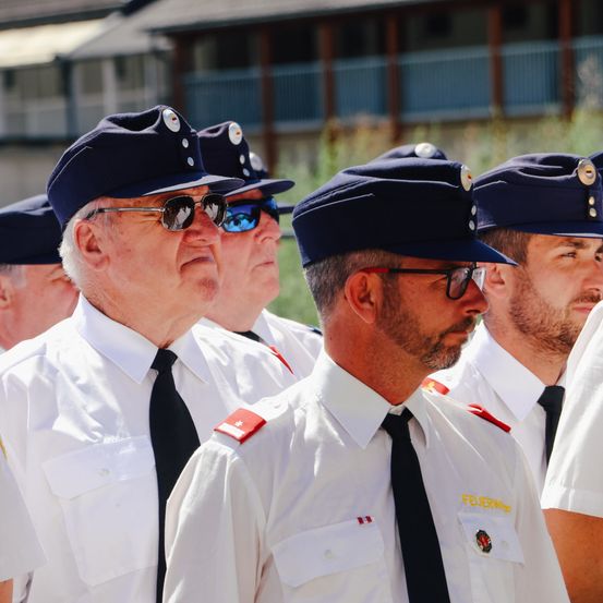 Eine Gruppe uniformierter Beamter steht in Formation, wobei ein älterer Offizier eine Sonnenbrille trägt und ein anderer Mann vorne ein Abzeichen trägt.