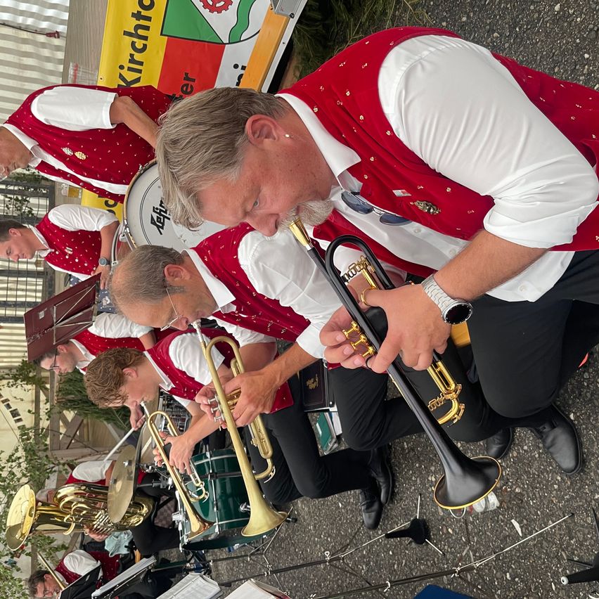 Eine Band spielt auf der Straße. Ein Mann spielt Trompete, während ein anderer Mann Posaune spielt.